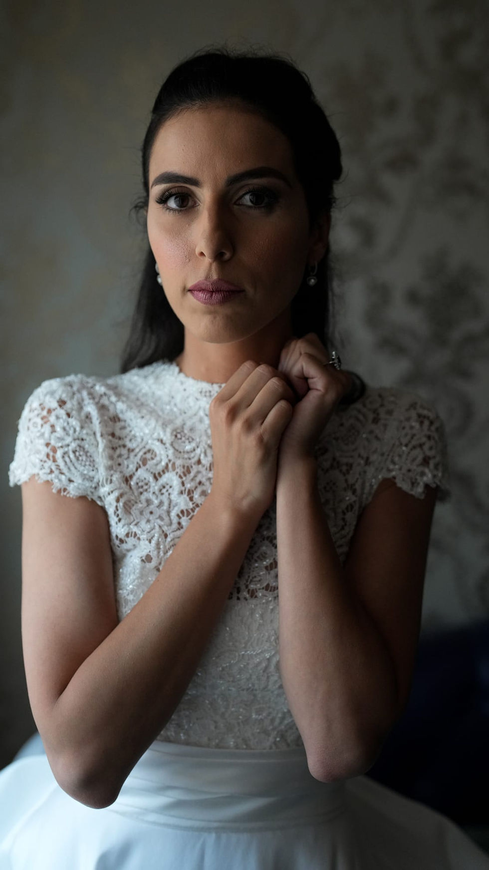 La sposa tocca delicatamente il suo velo, ritratto sereno ed emozionato prima della cerimonia.