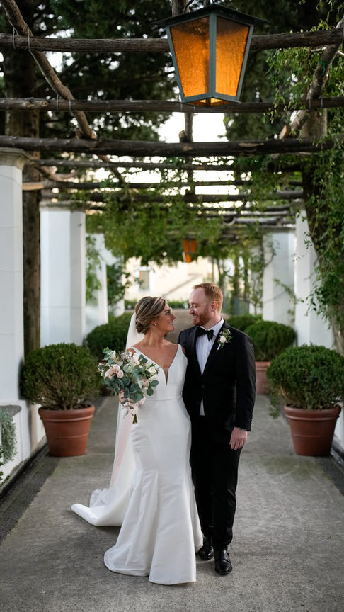 Bride and groom walking together under the arches of the villa, elegant architectural setting.