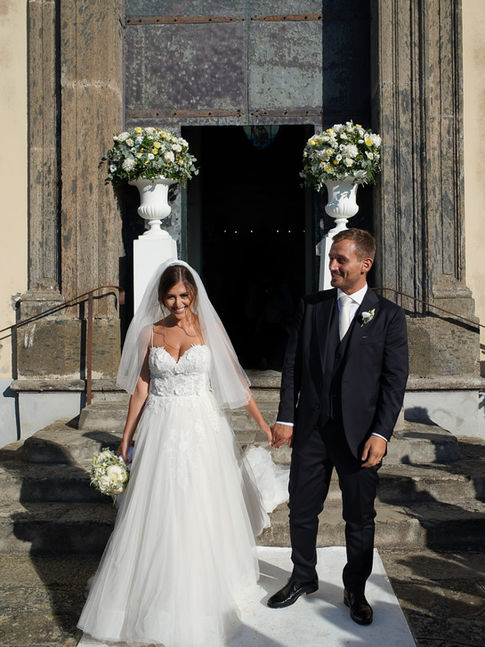 Bride and groom standing by the infinity pool at Relais Blu, overlooking the Amalfi Coast at sunset.