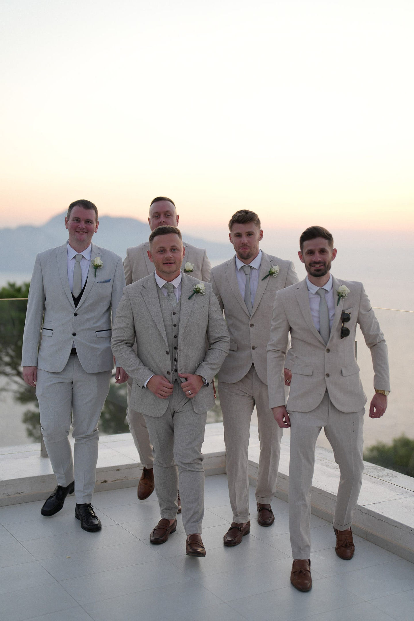 Groomsmen posing together in matching beige suits, relaxed and elegant look for a coastal Italian celebration.