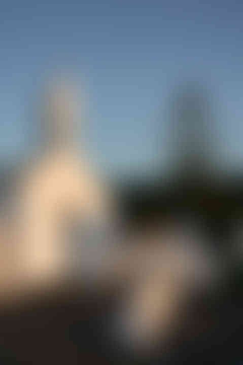 Bride standing in front of a white chapel at sunset, timeless destination wedding photograph.