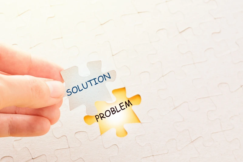 Hand holding piece of puzzle with word solution and putting it on place with problem