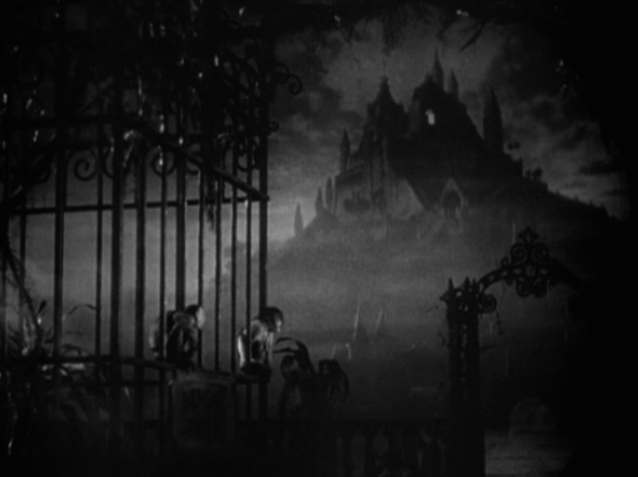 A gloomy, ominous mansion is foregrounded by a cage of monkeys