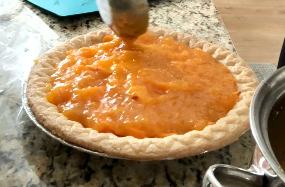 pouring peach pie filling on top of cream pie filling