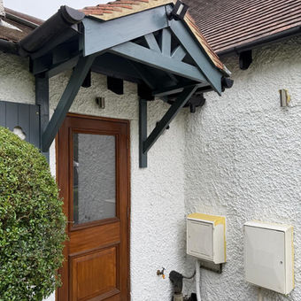 Side entrance refurbished by Topp Spec, showing repaired and repainted wooden door and frame, grey painted porch beams and soffit, and newly painted pebble dash walls.