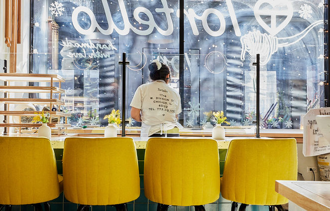Yellow stools at a counter with a Tortello logo and a patterned floor