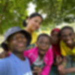 Group of five kids smiling and making faces under trees.