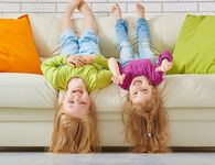 Children upside down on couch for article on nostalgia parenting and the benefits of childhood simplicity