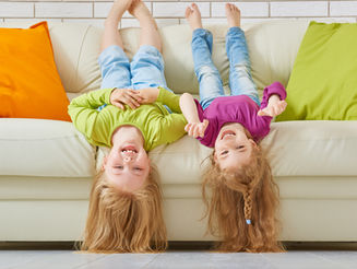 Children upside down on couch for article on nostalgia parenting and the benefits of childhood simplicity