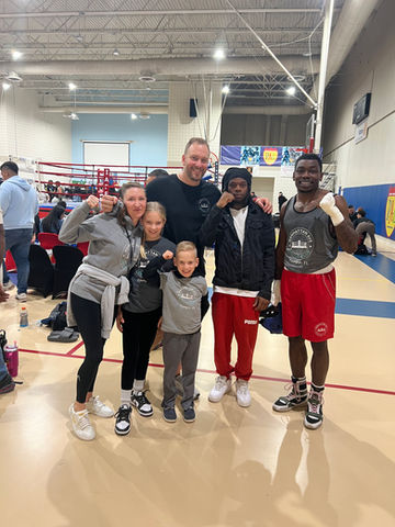 Group of people pose in a boxing ring setting for photo.