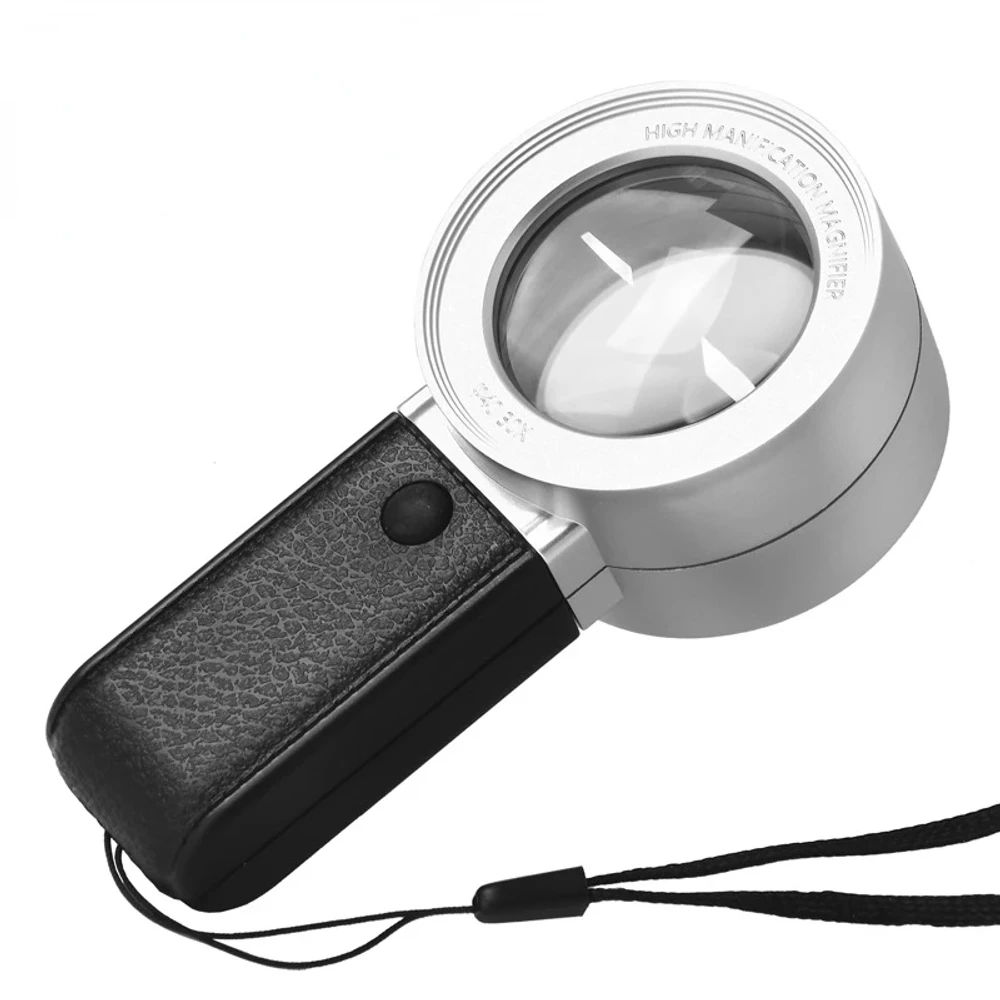 Lupa LED 30x con lente redonda gruesa en marco plateado que dice «High magnification magnifier», mango negro con textura de cuero, botón de luz y correa negra. (foto 1 de 4)