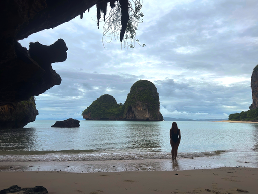 Woman's silhouette looking at lime stone cliffs coming out of the andaman sea.