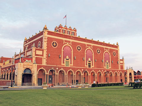 Golden-hour view of Asbury Park Convention Hall's ornate red-brick facade with arched windows and Beaux-Arts detailing
