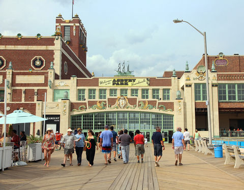 Tourists walking past the restored red-brick Asbury Park Convention Hall and Paramount Theatre on the boardwalk