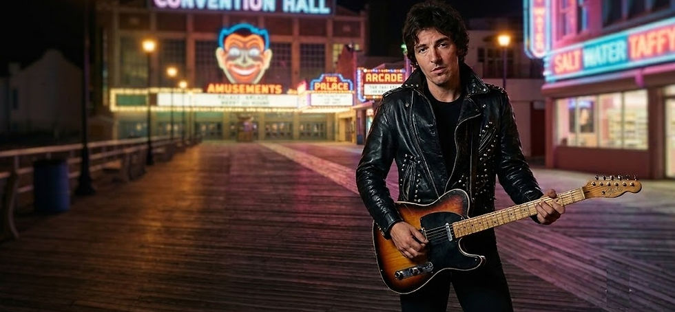 Musician posing with an electric guitar under the neon lights of Asbury Park's Convention Hall arcade at night