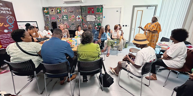 An audience of around 10-12 people listen as a female workshop leader delivers a presentation