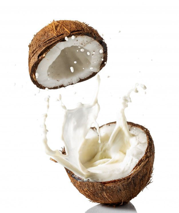 Premium Photo _ Broken coconut with a splash of milk on a white background