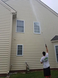 Man power washing side of beige house with water About cleaning purposes