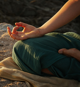 Handmudra tijdens een meditatieve yogasessie van Energy Source – natuurlijke rust en innerlijke focus op een rots bij zonsondergang in Alkmaar.