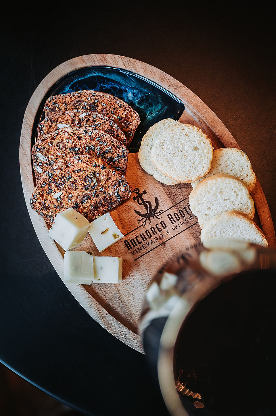 A view from the top of a styled charcuterie board that is engraved with the vineyard and winery logo "Anchored Roods"