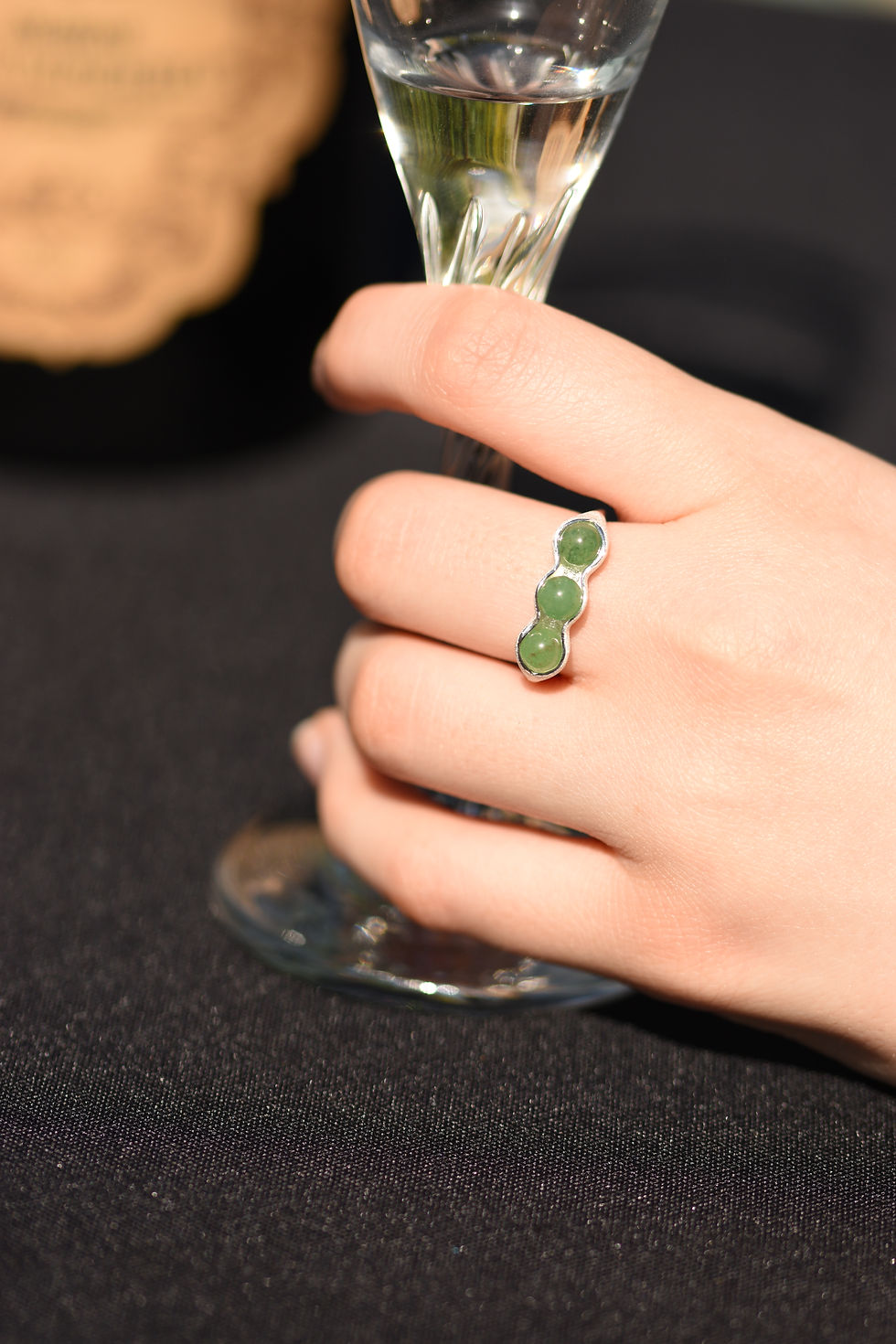 Silevr ring with green Aventurine gemstones on hand holding glass