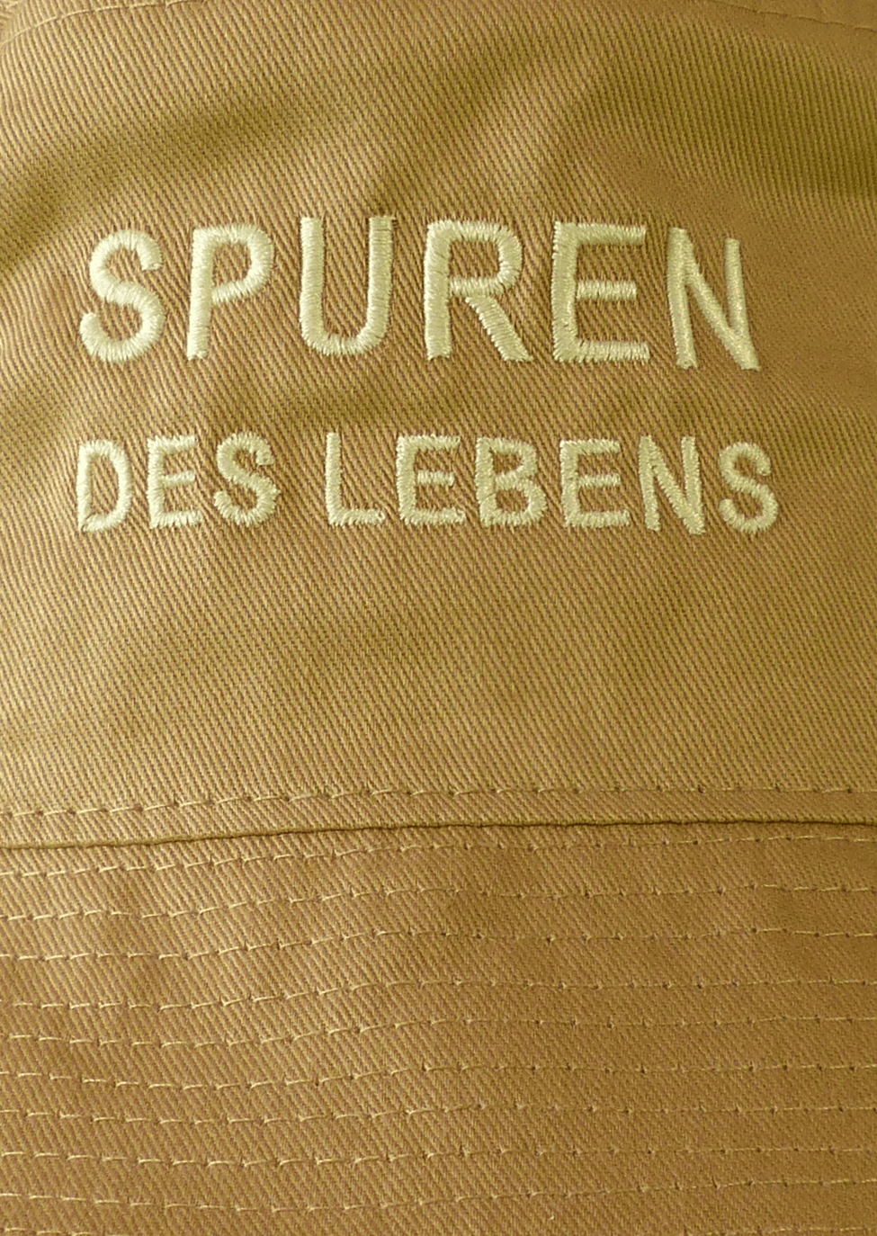 Miniaturbild: Detailansicht: Fischerhut khaki mit Spruch SPUREN DES LEBENS; Mützen von kahlkopf.ch geben Krebspatienten ein Gesicht