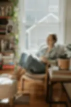 Woman enjoying coffee, smiling by window. Light and airy interior
