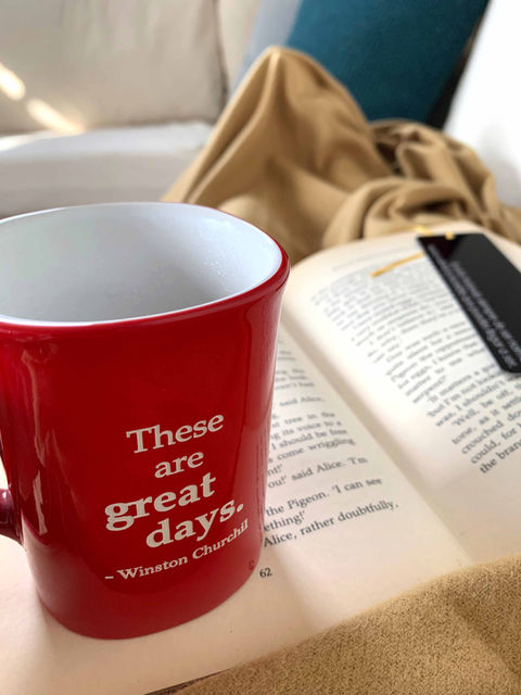 Taza roja sobre un libro grabada con la frase These are great days de Winston Churchill.