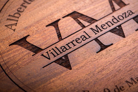 Tabla de madera grabada con monograma y el nombre de la familia.