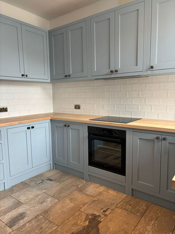 Bespoke kitchen with light blue shaker cabinets and timber worktops.