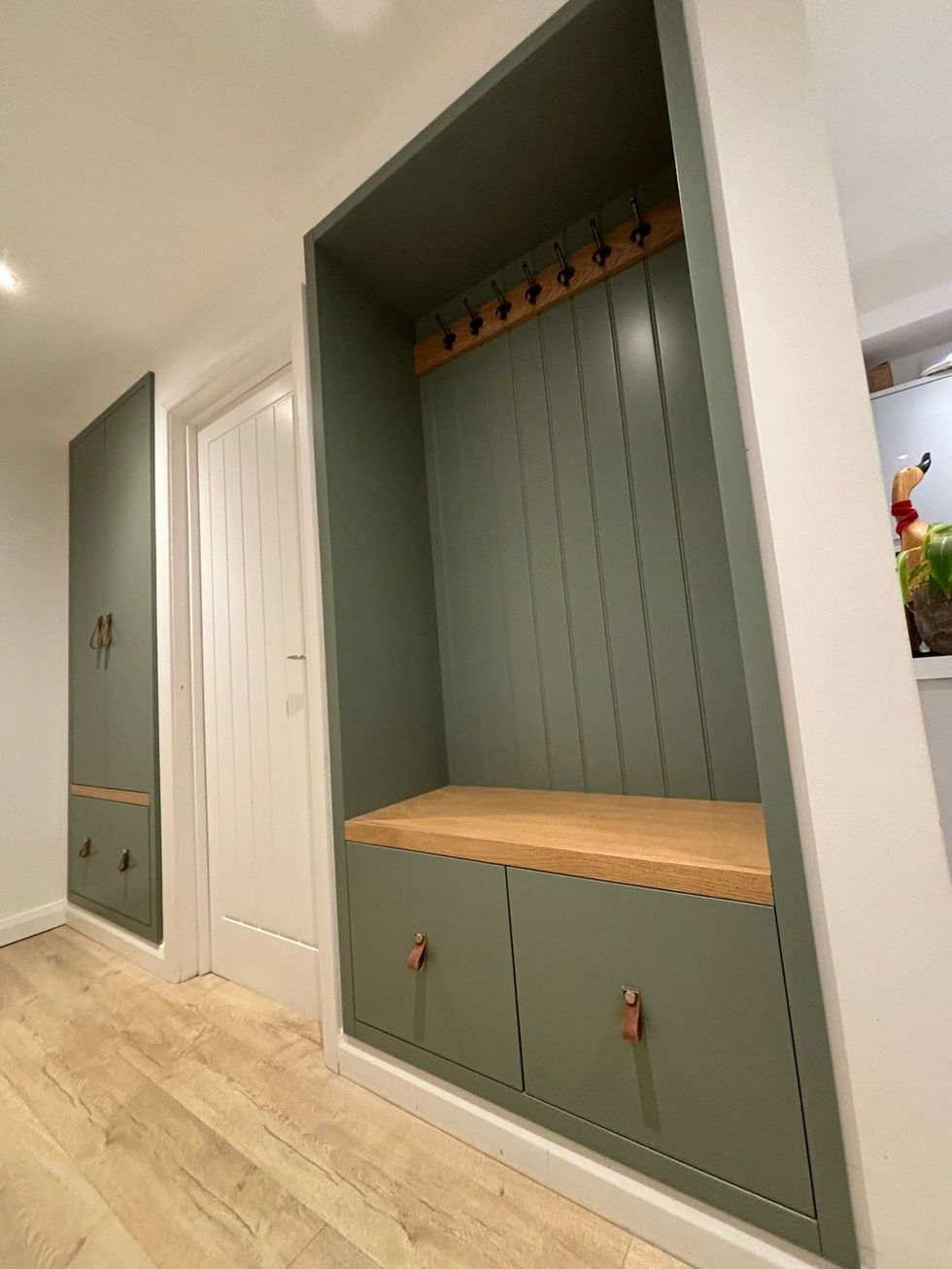 Custom hallway storage with bench seating, coat hooks and concealed compartments.
