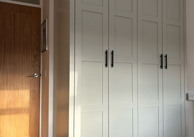 Fitted wardrobes with shaker doors, designed to maximise storage in a compact room.