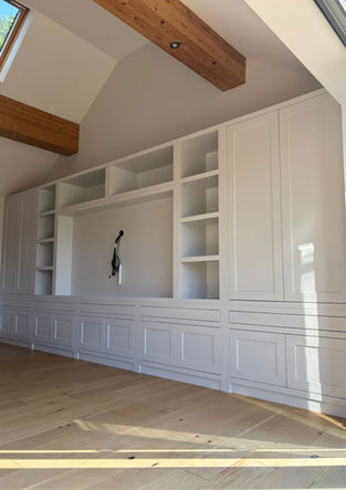 Long run of built-in cabinetry with painted doors, fitted beneath exposed ceiling beams.