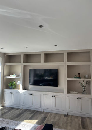Living room media wall with fitted cupboards, open shelving, and integrated TV.