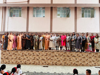 Group of women standing on a stage in front of a building.