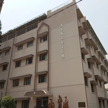 Modern building, 'SRI ANURAMALAYAM' text, solar panels, and statues at entrance.