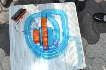 Solar-powered transparent blue marble run toy with purple marbles.
