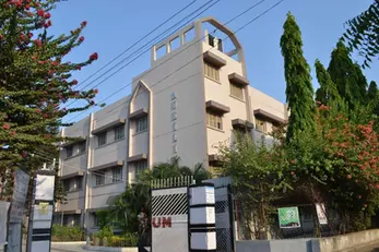 Modern building displaying ACCOLADES text, UM on gate, surrounded by trees.