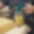 Hand holding a teal adhesive spray gun attached to a mason jar, spraying contact adhesive onto a block of upholstery foam.