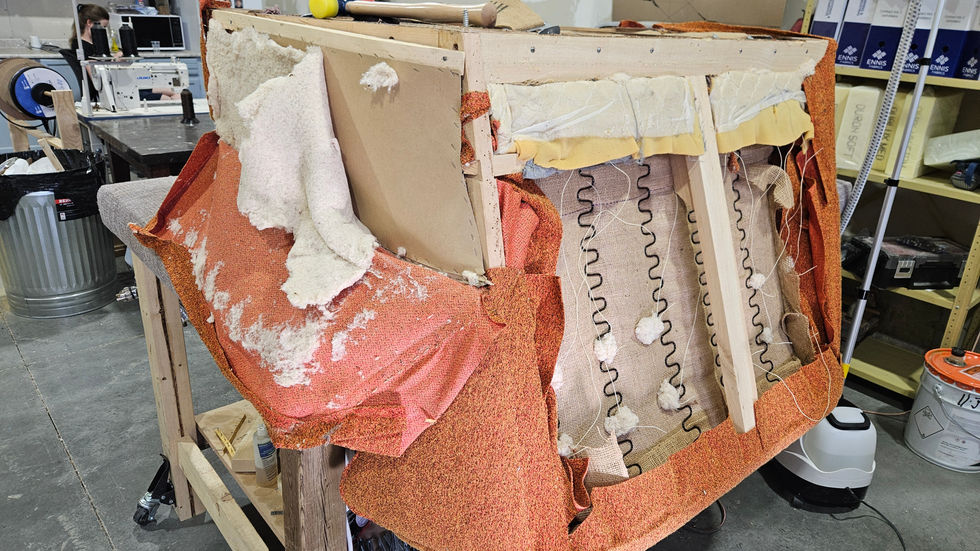 Partially stripped loveseat exposing webbing, springs, and natural cotton padding.