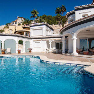 Witte villa met privézwembad, terras en palmbomen in Spanje.