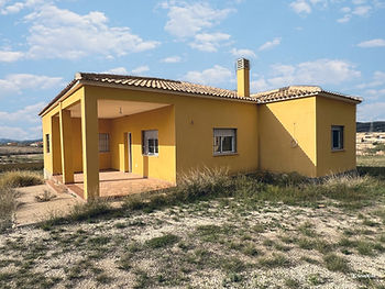 Geel-huis-met-pannendak-in-spanje-onder-blauwe-lucht