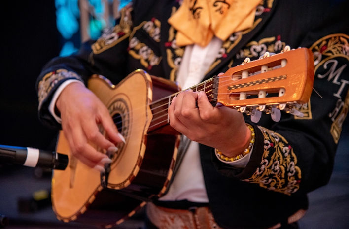 Close-up of mariachi guitarist playing acoustic guitar in charro suit