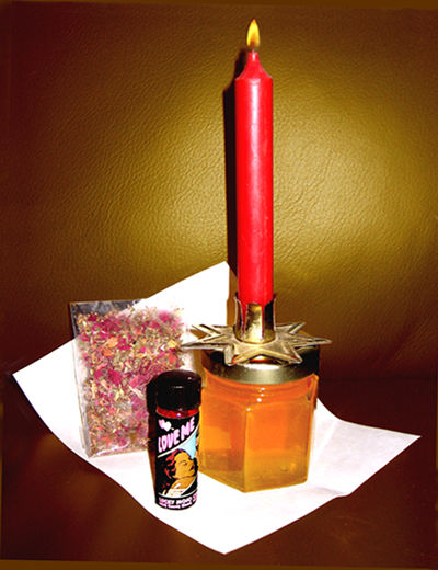 A candle, herbs, and perfume bottle arranged together on a surface.