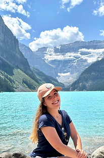 foto de uma mulher em frente a um lago azul com montanhas no fundo