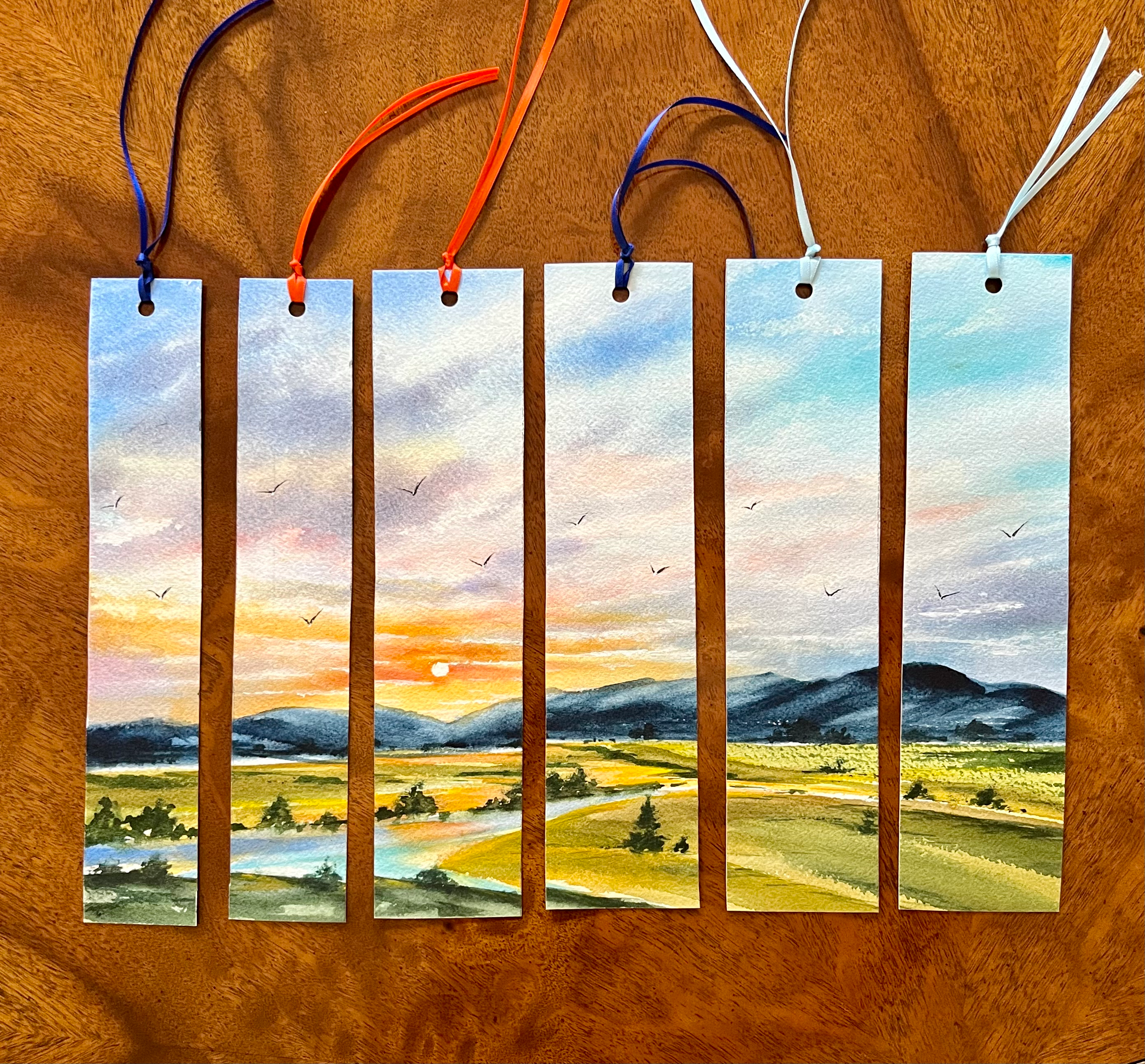 hand painted watercolor bookmark of a sunset over a mountain range