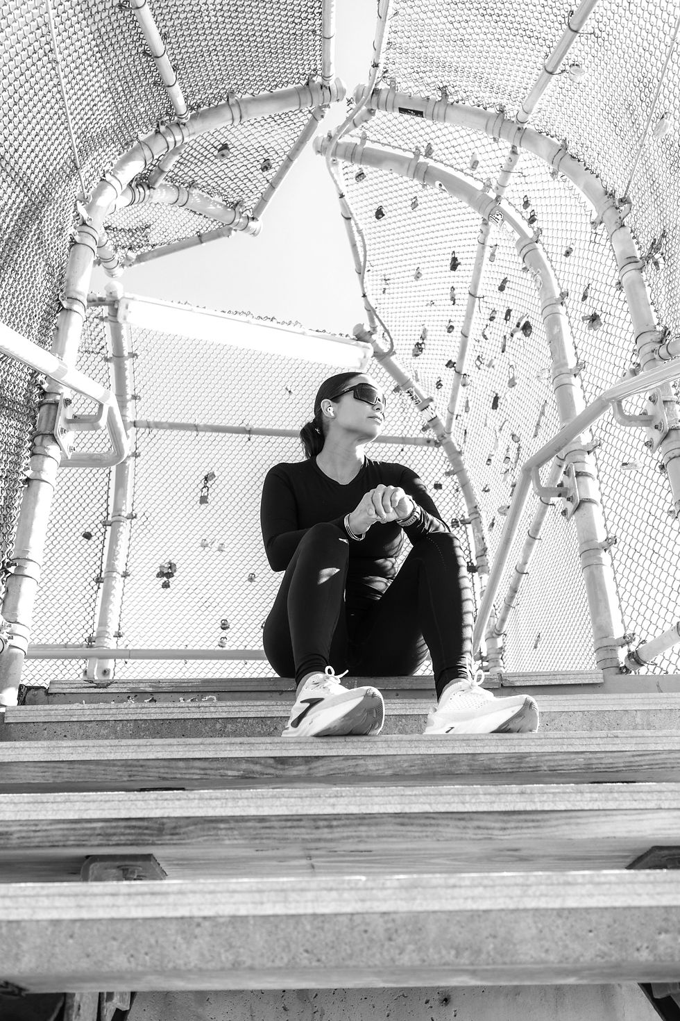 Woman in athletic clothes sitting on stairs wearing headphones.