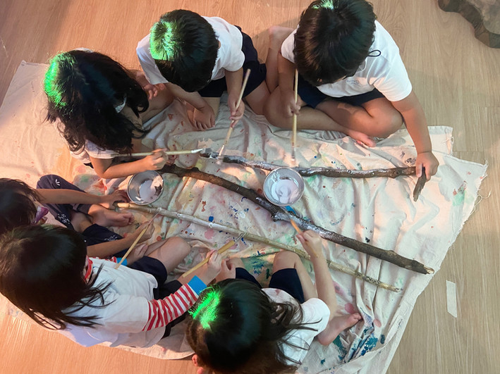 Children using mod podge on branches.