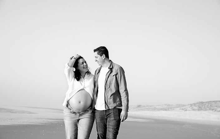 Séance photo de grossesse en extérieur sur la plage, capturant une future maman au coucher du soleil avec une lumière naturelle douce et des tons chaleureux.