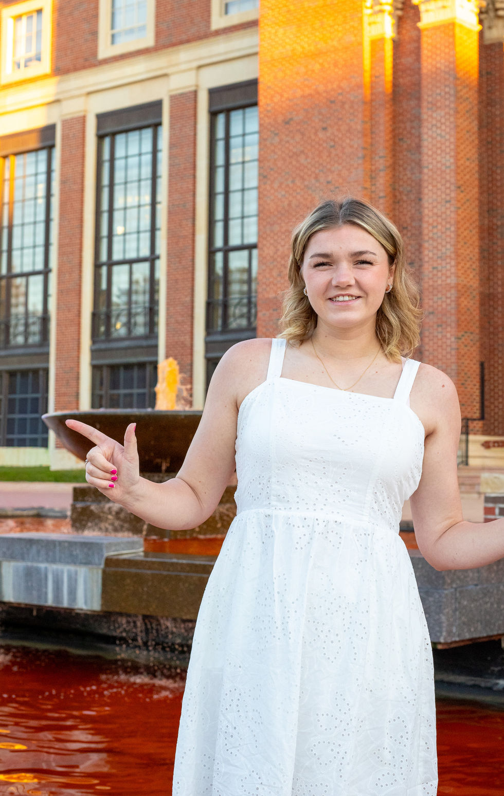 A girl standing in a fountain with the water dyed orange